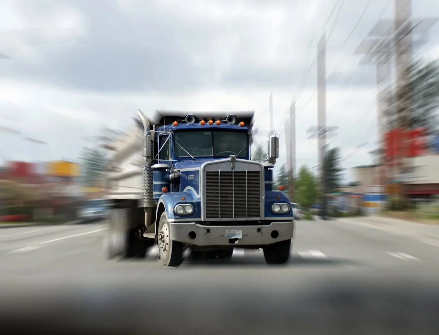 A truck driving down the street with a sky background